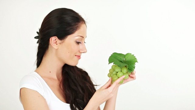 Young attractive woman playing and eating green grape