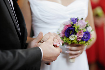 Obraz na płótnie Canvas Groom holding bride's hand during the wedding ceremony