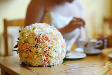 Bridal wedding bouquet on a table (bride on a background)