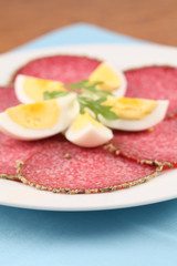 Salami with pepper crust and eggs on a plate
