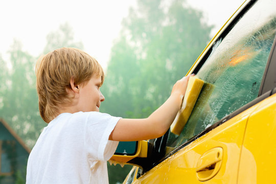 Little boy washing car. Summer. Sunset