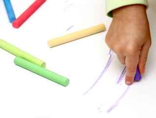 child drawing colour lines with chalk
