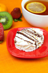 lemon tea, kiwi,cake and strawberries lying on the orange fabric