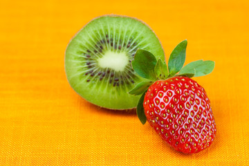 mandarin and strawberries lying on the orange fabric