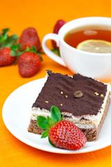 lemon tea, cake and strawberries lying on the orange fabric