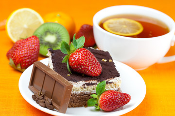 lemon tea,chocolate, kiwi,cake and strawberries lying on the ora