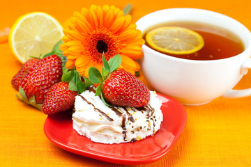 lemon tea ,lemon,gerbera,cake and strawberries lying on the oran