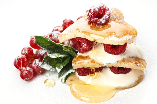 Heart shaped pancakes topped with honey, raspberries, mint and P