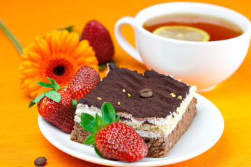 gerbera, lemon tea, cake and strawberries lying on the orange fa