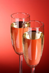Two glasses of champagne on a red background