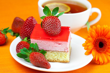 gerbera, lemon tea, cake and strawberries lying on the orange fa