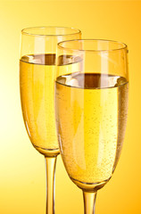 Two glasses of champagne on a yellow background