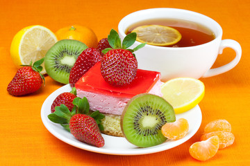 lemon tea, kiwi,cake and strawberries lying on the orange fabric