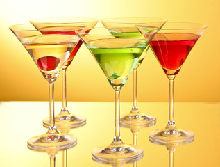 a few glasses of alcoholic drinks in a yellow-brown background