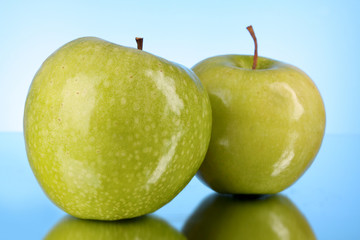 Two green apples on blue background