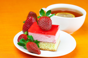 lemon tea, cake and strawberries lying on the orange fabric