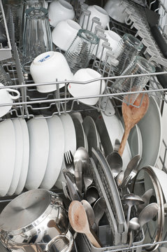 Dish washer with clean and shiny dishes and kitchenware