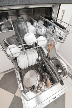 Dish washer with clean and shiny dishes and kitchenware