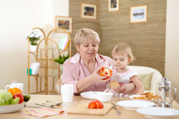 grandmother feeding granddaughter at home