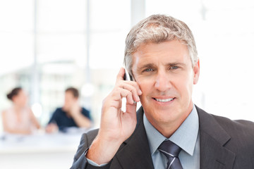 Businessman phoning while his team is working