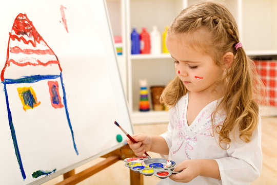 Little artist girl painting on large paper canvas