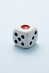 水色の背景に1個の賽子のアップ