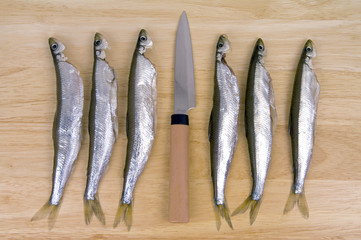 Refined smelt and knife lie on a wooden chopping board