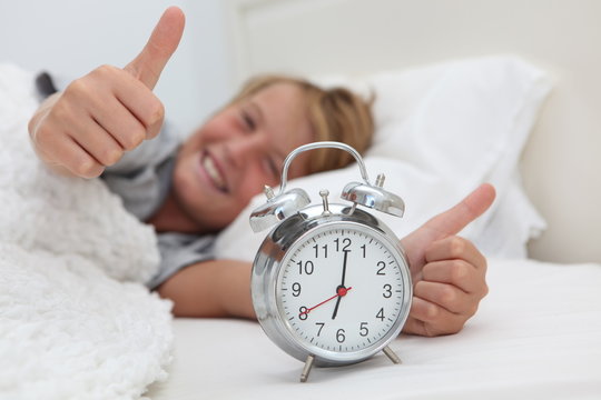 child with clock waking up happy