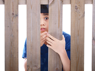 child looking through a fence