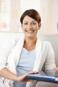 Portrait of happy woman holding laptop