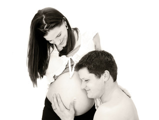 toned image of father listening to mother's pregnant belly.