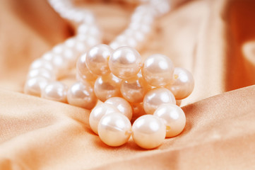 Pearl necklace on the bright satin background