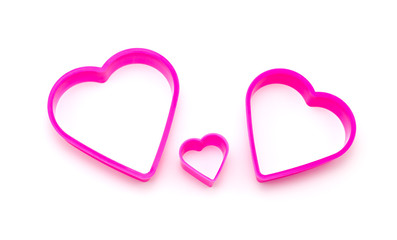 row of pink plastic pieces in heart shape isolated on white