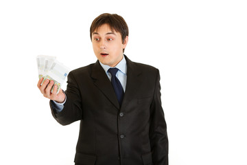 Surprised modern businessman holding money in his hand