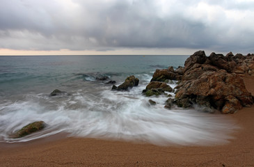 Seascape with motion blurred waves hitting the rocks