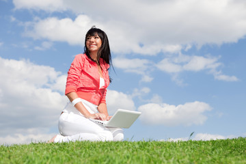 Naklejka na ściany i meble Cute woman with white laptop in the park