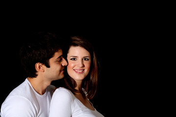 Loving couple on dark background: boy giving a kiss