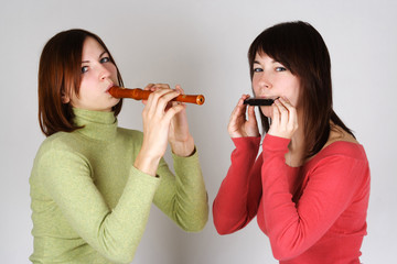two brunette girls in bright shirts playing on flute and harp, l