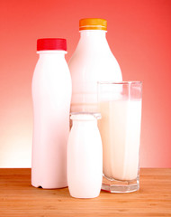 glass of milk and bottle on red background