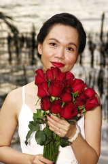 young woman with red roses near the river