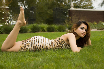 Exotic brunette laying on stomach in the grass