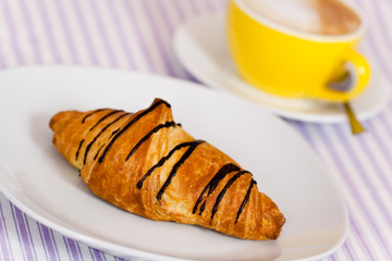 Cappuccino mit Croissant mit Schoko-Überzug