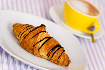 Cappuccino mit Croissant mit Schoko-Überzug