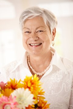 Portrait of elderly woman holding flowers