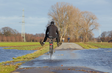 Radfahrer fährt durch Überschwemmung