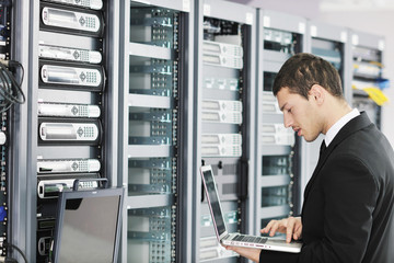 businessman with laptop in network server room