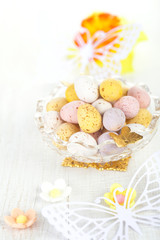 Obraz na płótnie Canvas chocolate speckled eggs in bowl with paper batterfly on white ta