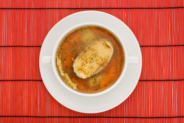 Soup with salmon and hot peppers on a red background