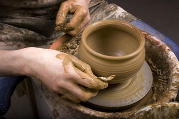 The hands of a potter, creating an earthen jar on the circle