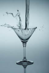 Clear liquid pour into wineglass toned in blue